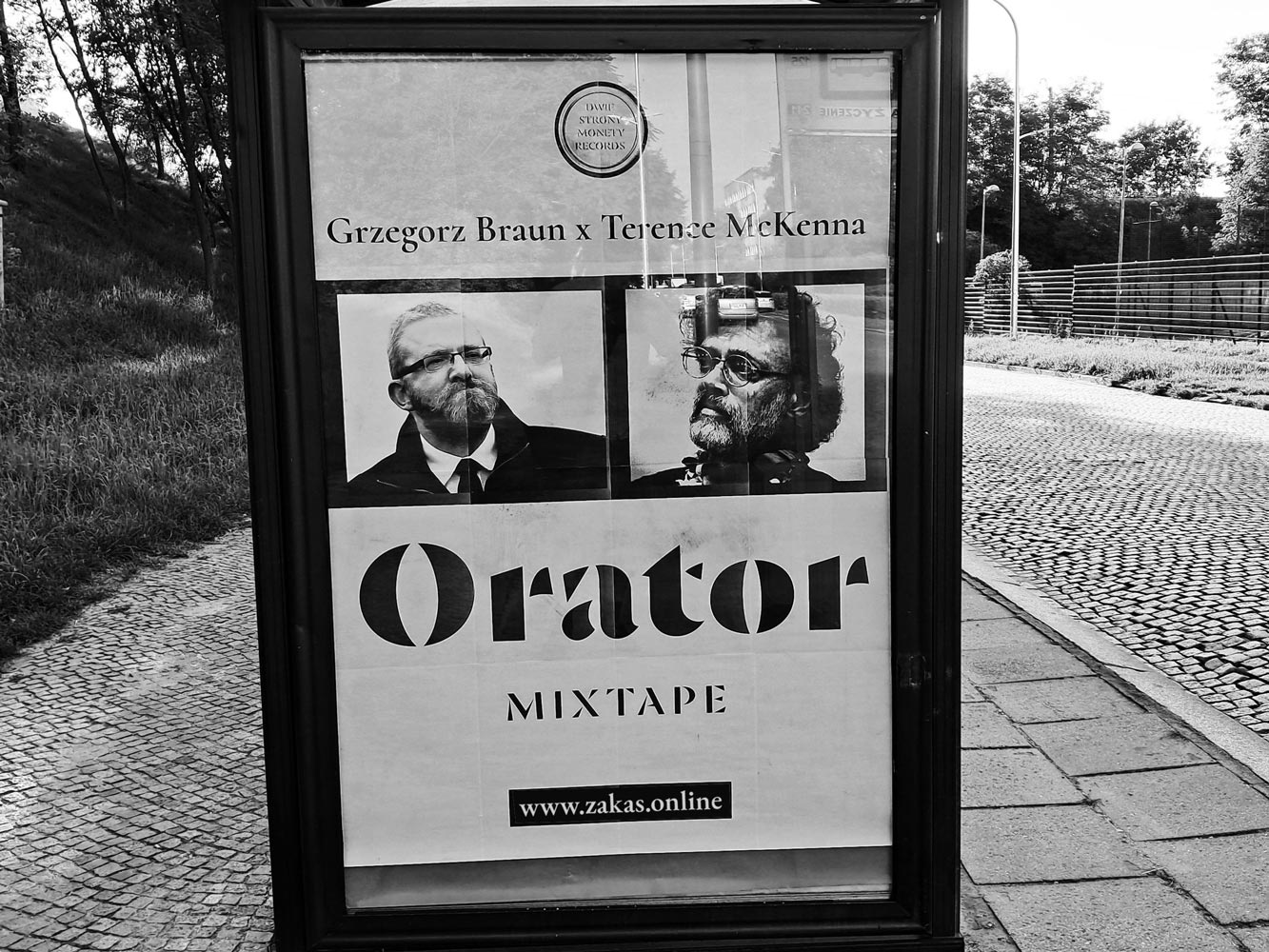 Plakat na przystanku ze zdjęciami Grzegorza Brauna i Terrence McKenna i podpisem "Orator Mixtape"